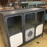 Industrial metal cabinet, with stencilled panels and glass in the doors.